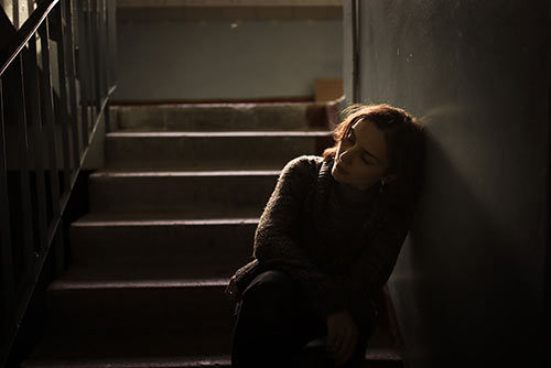 woman sitting in dark stairwell