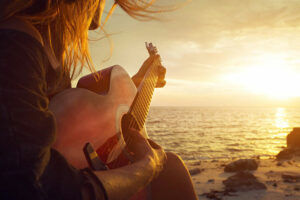 women playing guitar on beach
